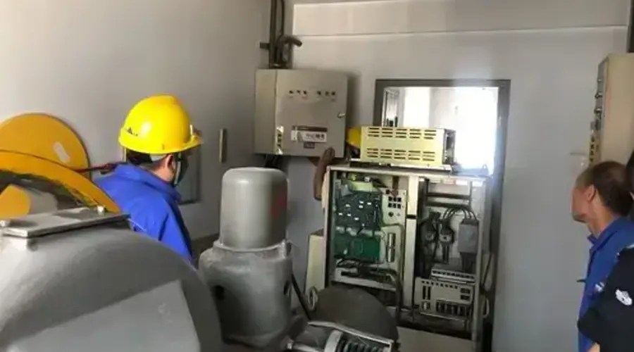 یک تعمیرکار در موتورخانه آسانسور در حال نگاه کردن به اجزای آسانسور
